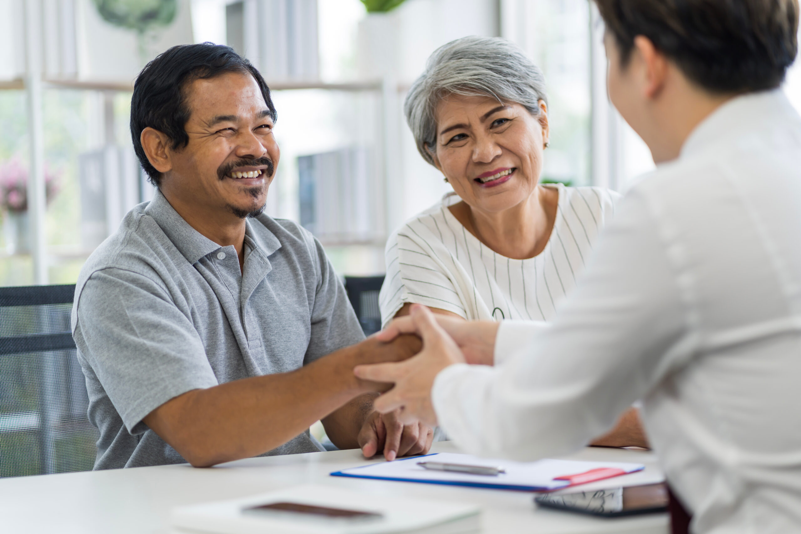 A middle-aged couple approaching retirement shakes hands with their financial advisor