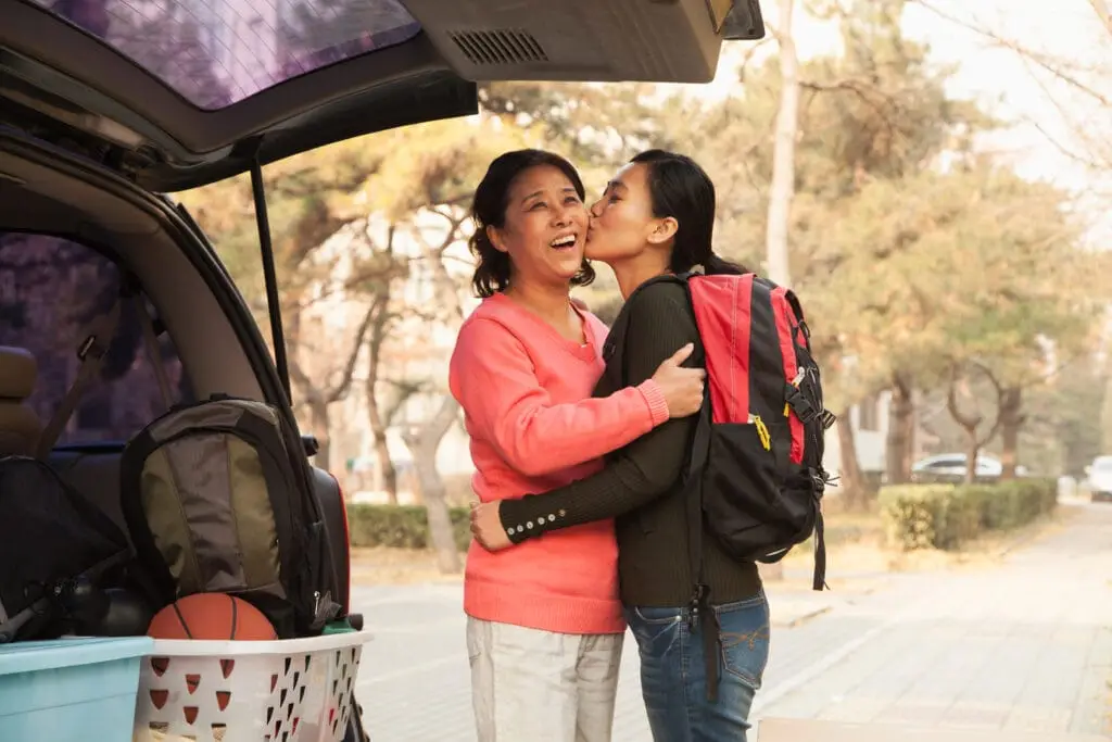 A young daughter kisses her mother on the cheek as she gets dropped off for college. Careful financial planning is key to making college attainable in Arizona.
