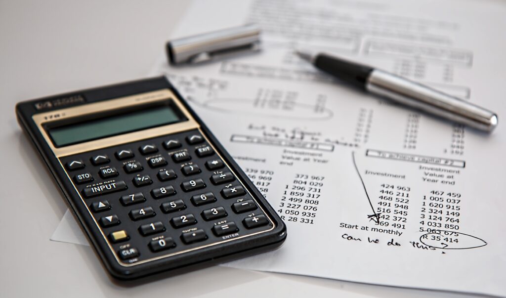 calculator and pen resting on page showing investment returns