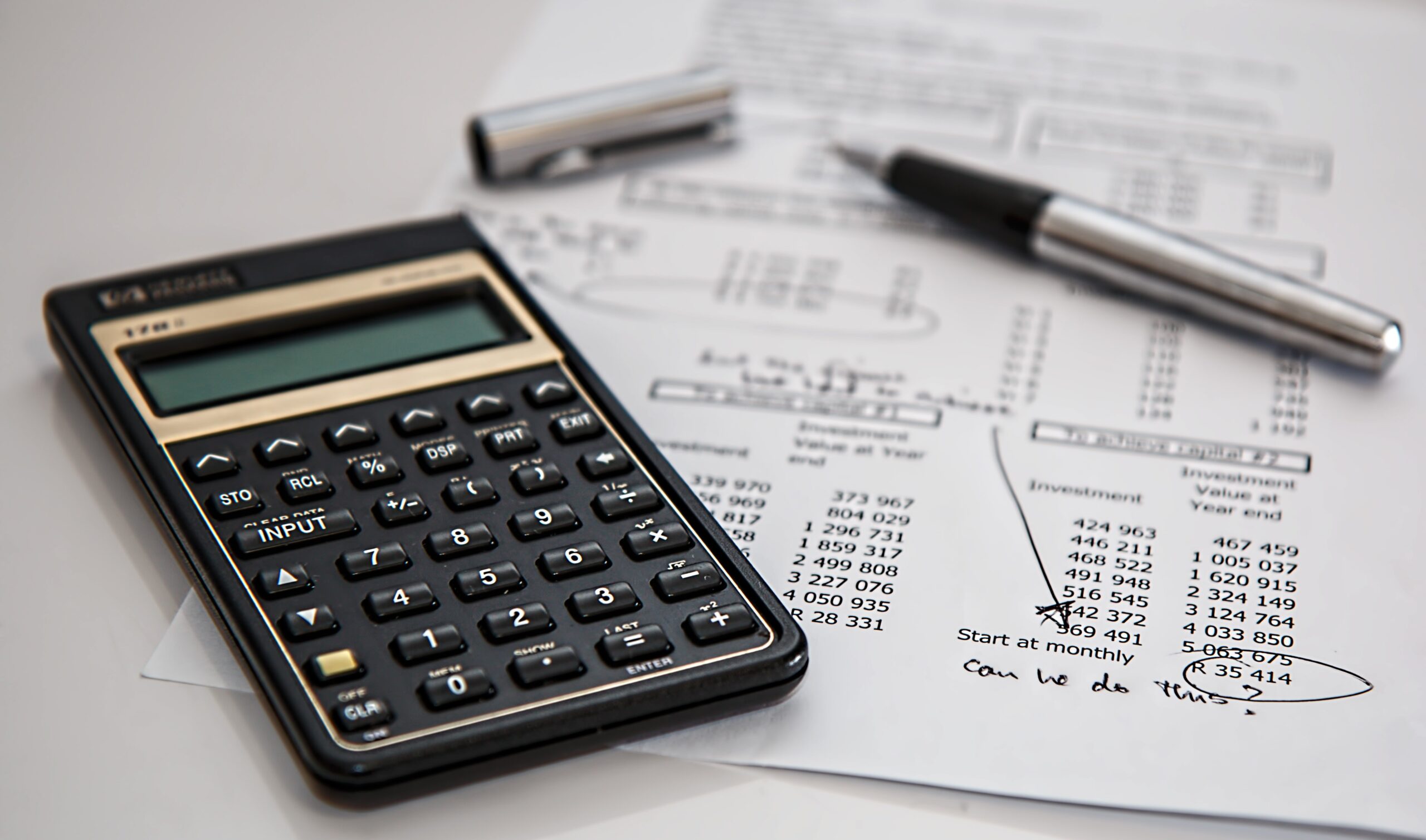 calculator and pen resting on page showing investment returns