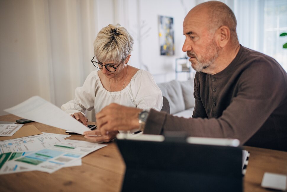 An older couple reviewing financial documents at their dining room table